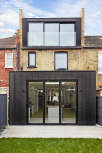 The loft conversion features a master bedroom with an en-suite bathroom and full-height glazed sliding windows that open onto French balconies, offering expansive garden views.