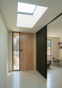 Entrance hall with skylight, natural color scheme, warm wood tones, and modern design.